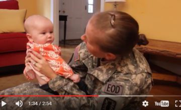 video still of woman in military uniform smiling at baby